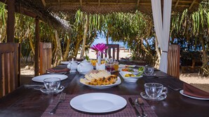 Une table à manger dressée pour un repas, avec des assiettes, des couverts et une variété de plats.