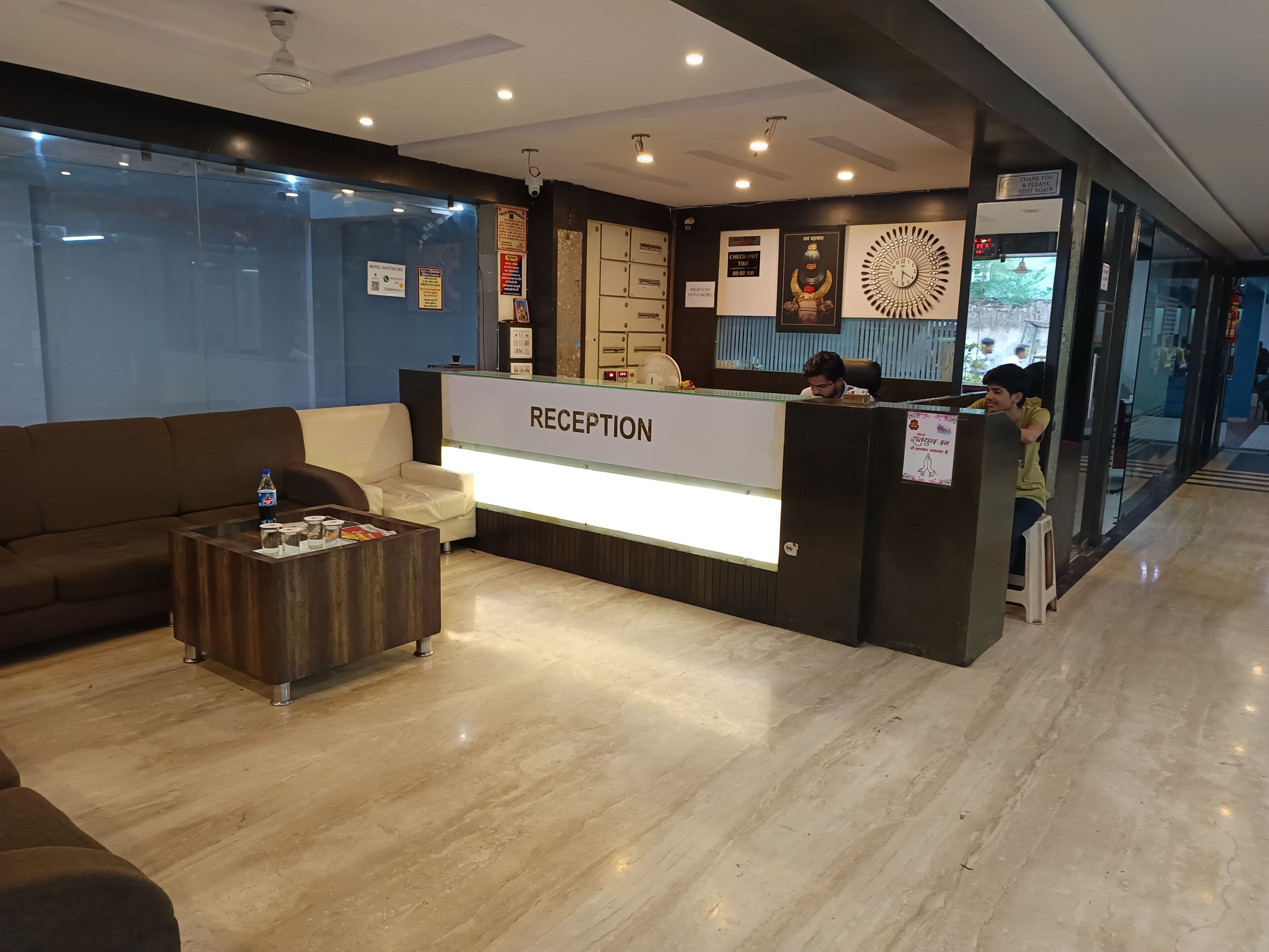 Un área de recepción con mostrador, un sofá, una mesa de centro y un reloj en la pared.