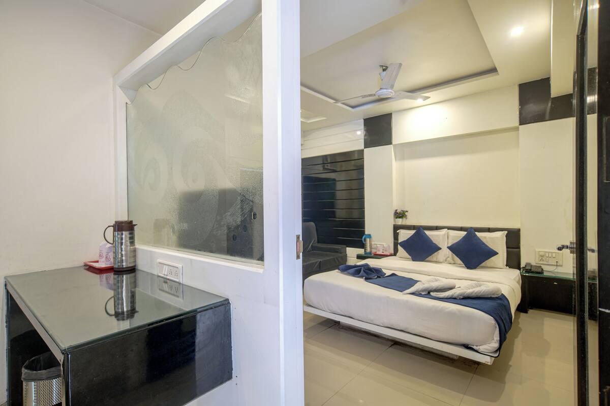 A modern hotel room with a bed, bedside table, and a window.