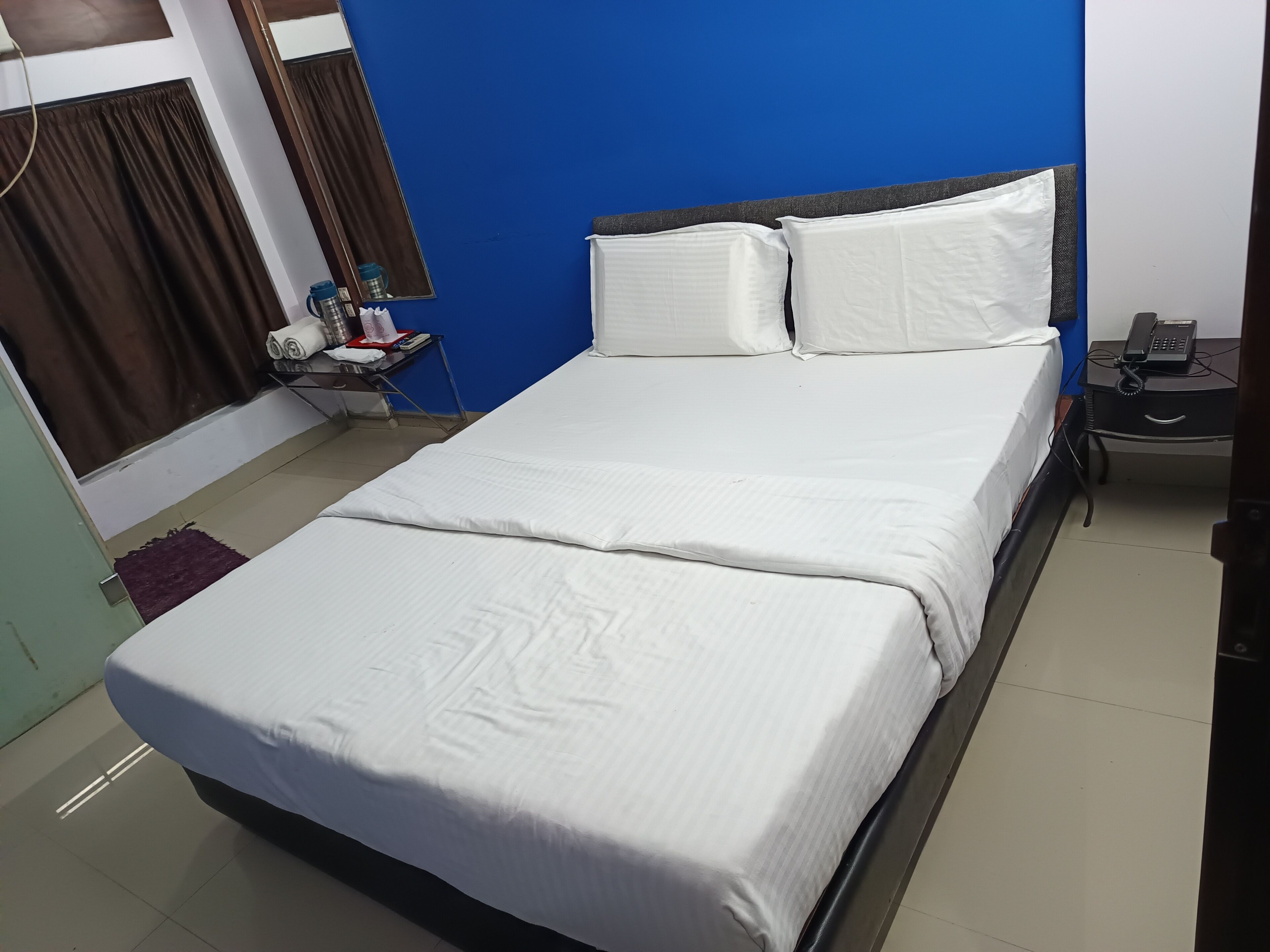 Una cama bien tendida con sábanas blancas en una habitación con paredes azules.