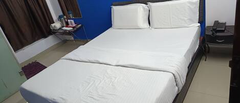 Una cama bien tendida con sábanas blancas en una habitación con paredes azules.