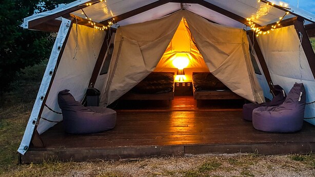 A tent with a wooden deck, two bean bags, and string lights. - Saros Tepe Camping (Gallipoli)