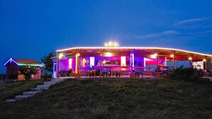 A building with a covered outdoor area, a flag, and steps leading up to it. - Saros Tepe Camping (Gallipoli)