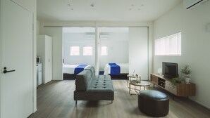 A modern hotel room with a sofa, ottoman, TV, and a small side table. - Seacruise House Navio (Kamiamakusa)