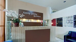 A reception desk with a sign reading 'Kipang Gunung Residence,' a potted orchid, and a blue sofa. - Hotel O Surabaya near Surabaya Town Square formerly Kupang Gunung Residence (Surabaya)