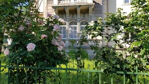 A building with ornate architecture, a green metal fence, and flowering bushes. - Hotel Villa Lalee (Dresden)
