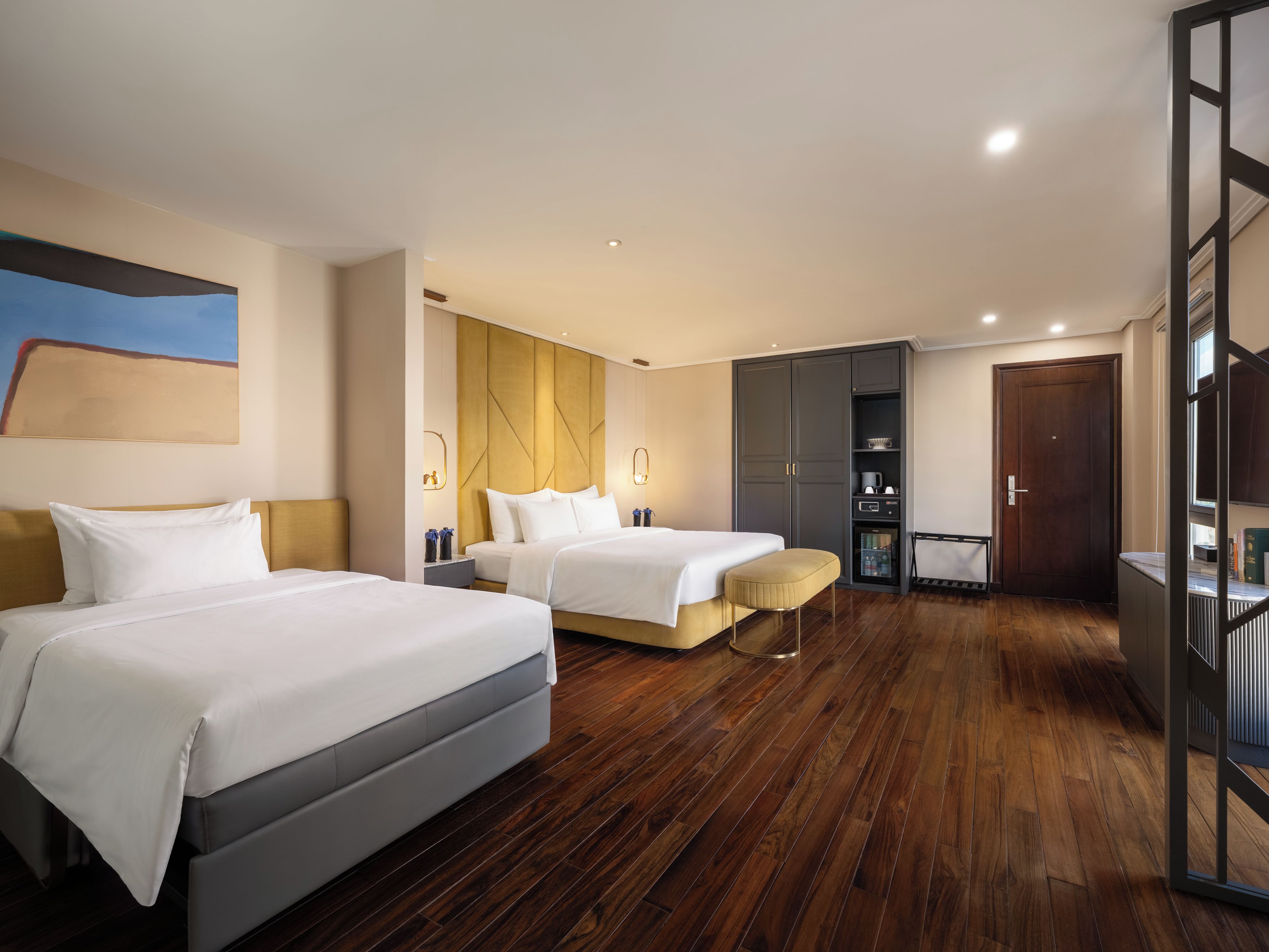 Een hotelkamer met twee bedden, een houten vloer, een kledingkast en een zithoekje.