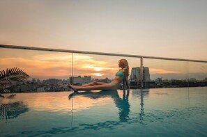 A person sitting on an infinity pool with a cityscape view in the background. - Soleil Boutique Hotel (Hanoi)
