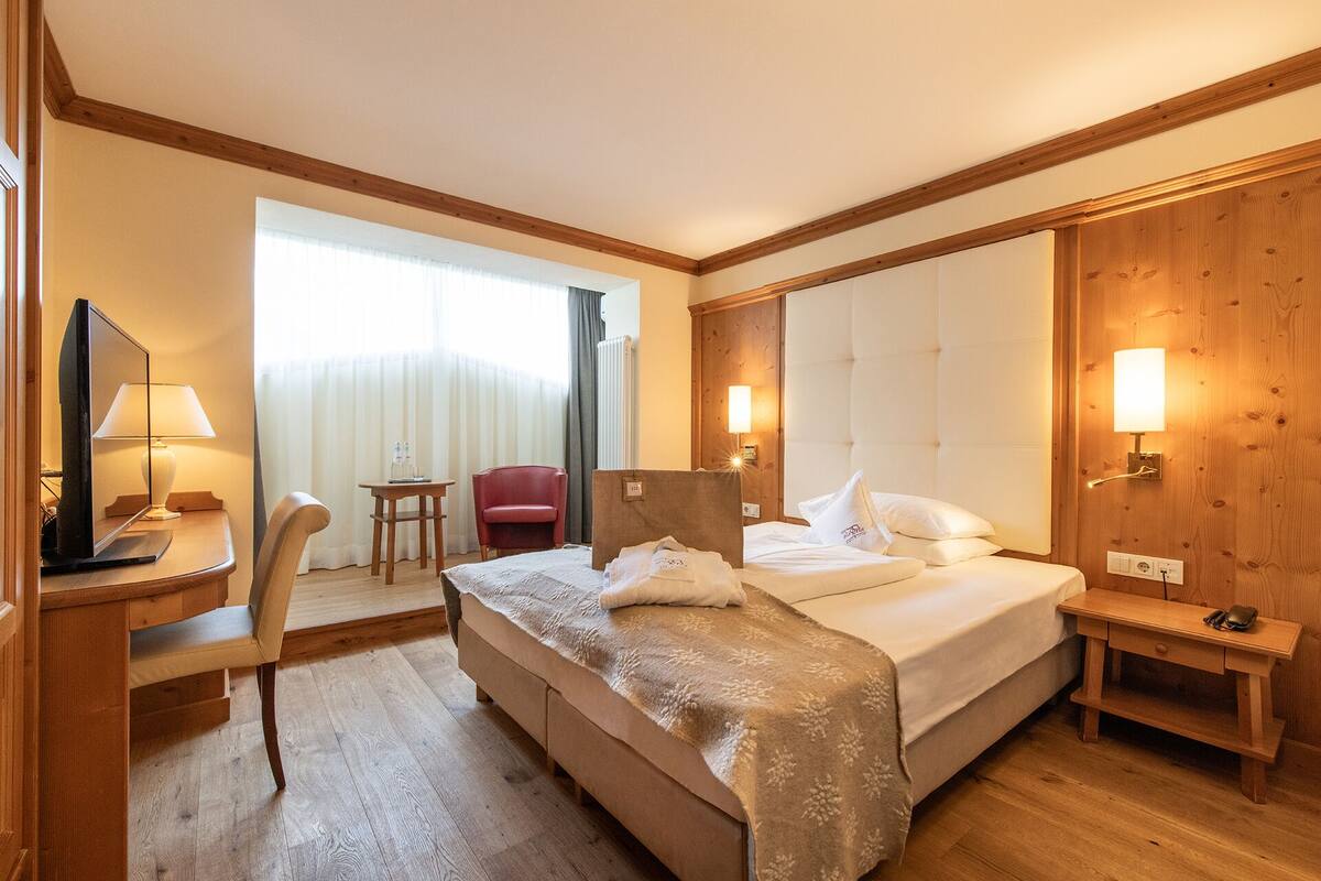 Une chambre d’hôtel avec un lit, un bureau doté d’une lampe, une chaise et une petite table.