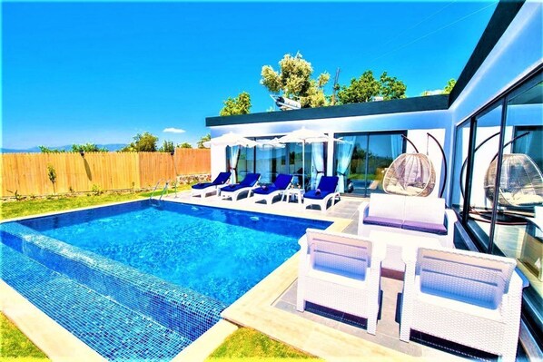 Una piscina al aire libre, sombrillas, tumbonas