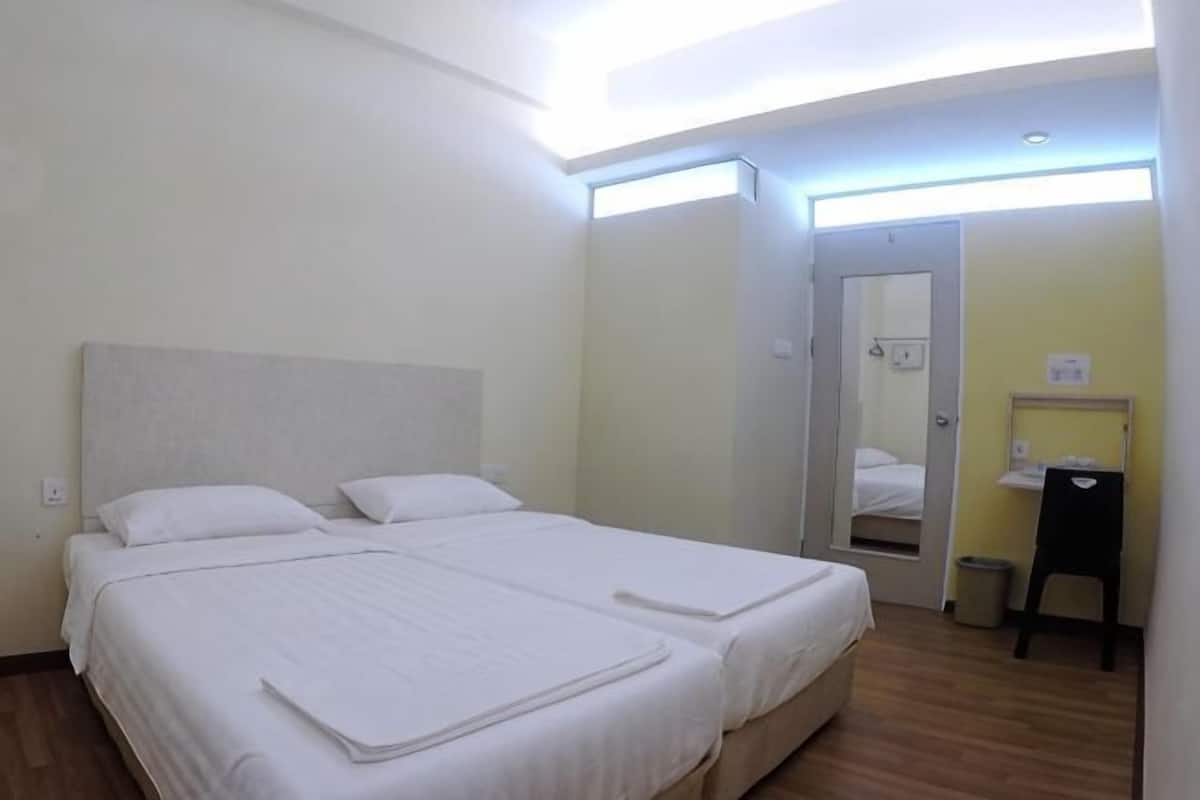 A double bed with a headboard, a bedside table, a mirror, and a door leading to a bathroom.