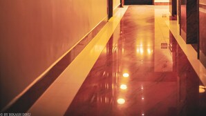 A hotel corridor with a polished floor, wooden doors, and wall-mounted lights. - Golden Kuensel  Resort & Spa (Kalimpong)