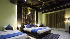 A hotel room with two beds, a large painting on the wall, a patterned curtain, and a decorative rug. - Golden Kuensel  Resort & Spa (Kalimpong)