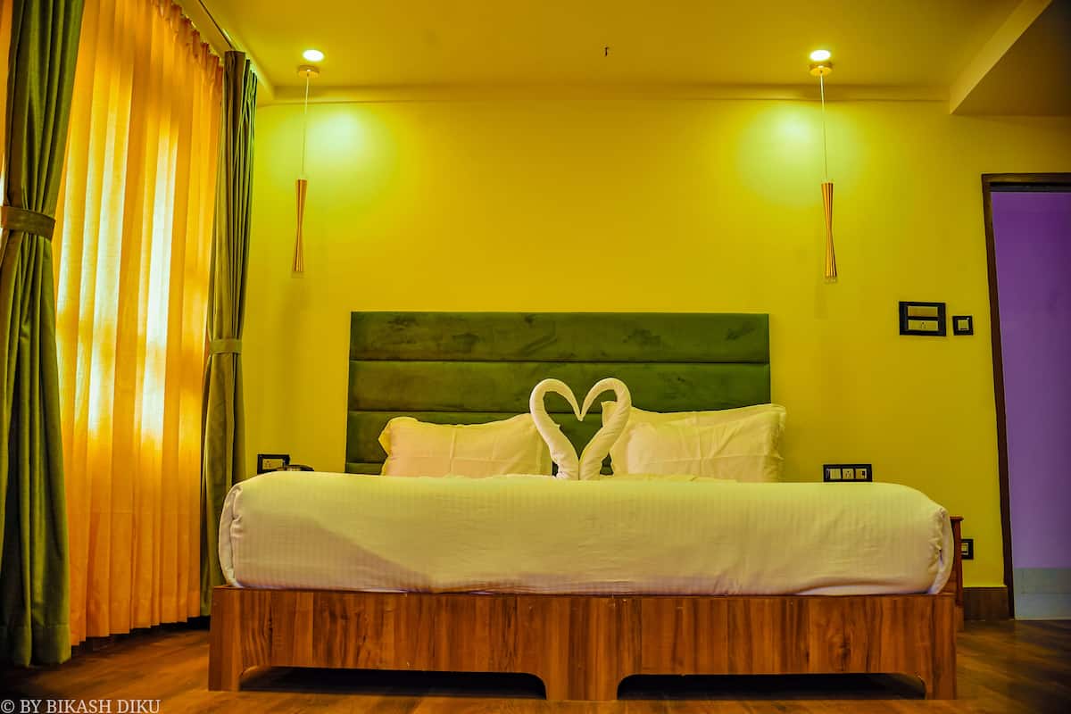 A hotel room with a wooden headboard, a bed with white bedding, and a heart-shaped decoration on the pillows.