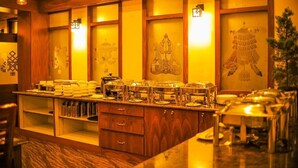 A buffet setup with various food containers and a wooden cabinet. - Golden Kuensel  Resort & Spa (Kalimpong)