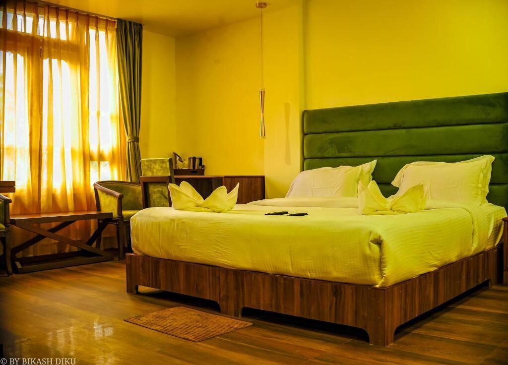 A hotel room with a large bed, wooden headboard, and a small desk with a chair.