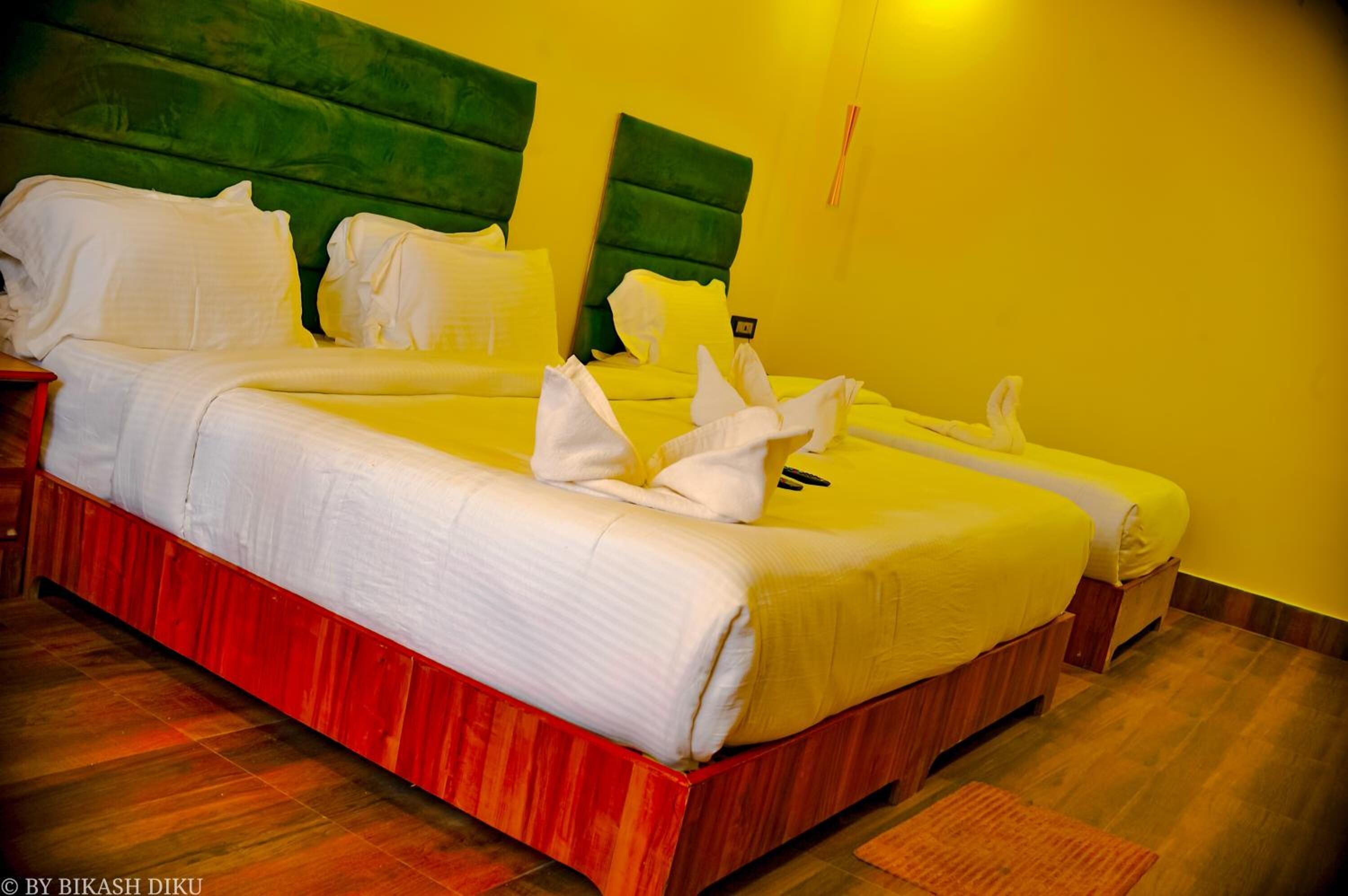 A hotel room with a large bed, two bedside tables, and a green headboard.