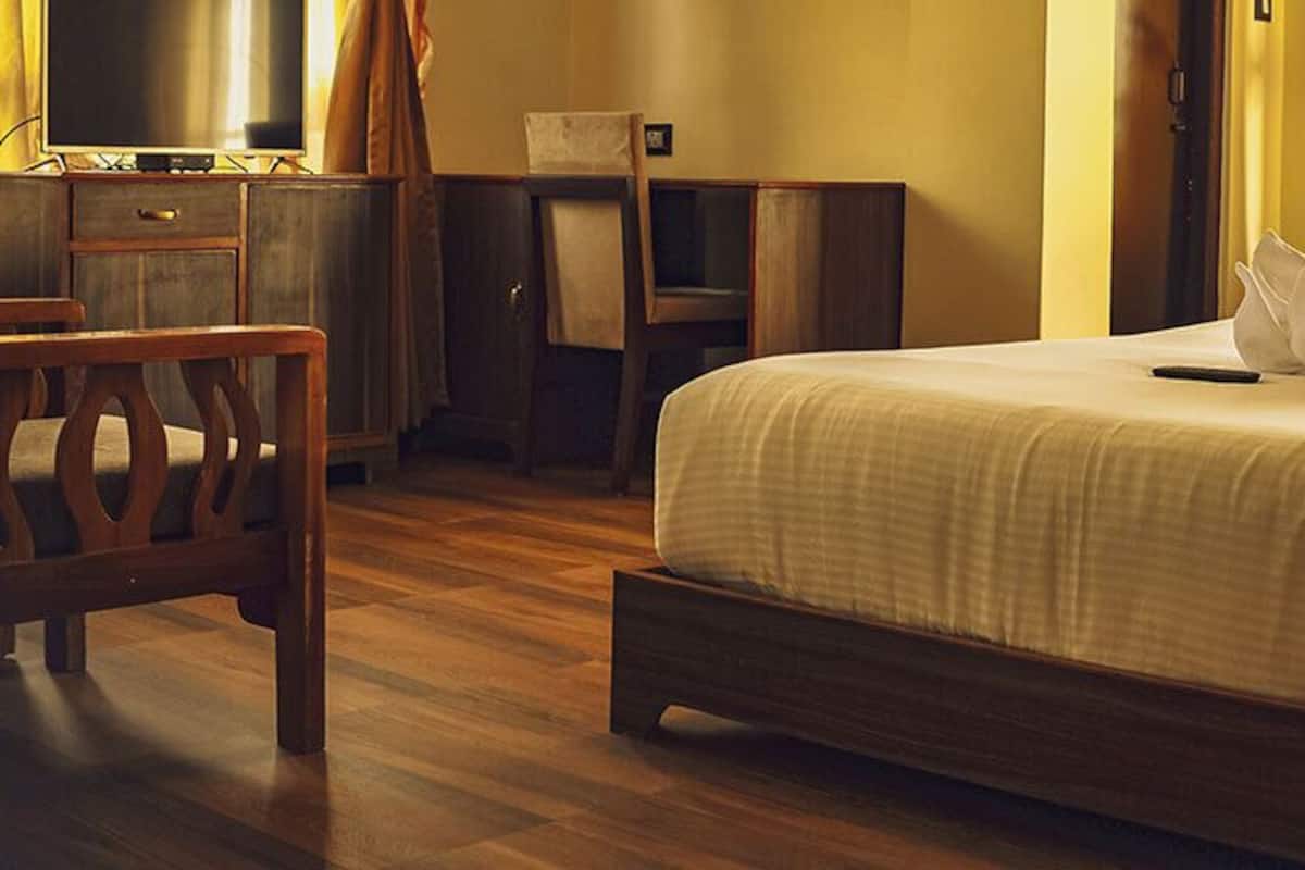A hotel room with a bed, a desk, a chair, a television, and curtains.