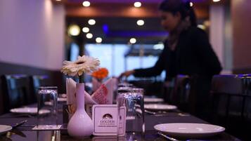 A dining table set with a vase of flowers, a menu, and a glass of water.