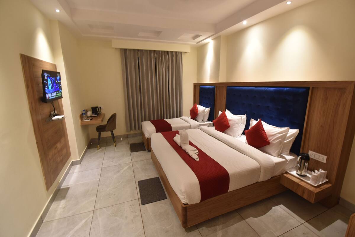 Habitación de hotel con una cama grande, un escritorio, una silla, un televisor y una ventana con cortinas.