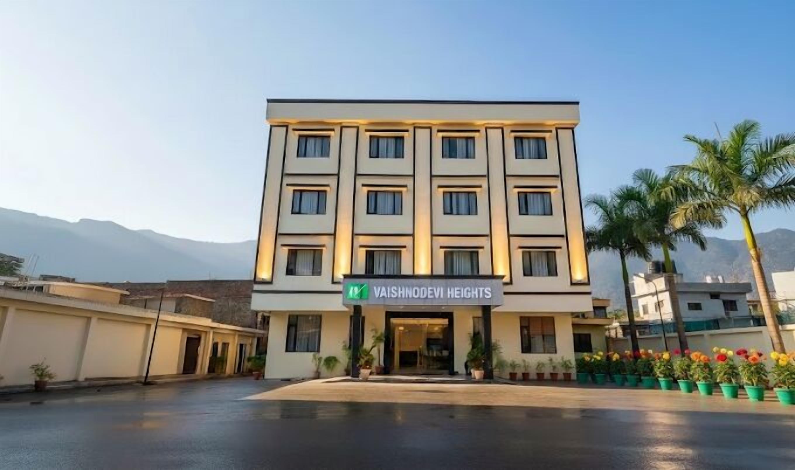 A multi-story hotel with a sign reading 'Vaishnodevi Heights.'