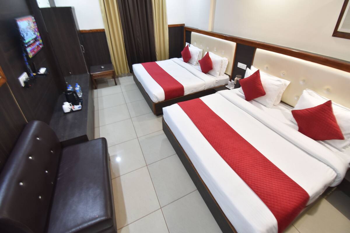 Habitación de hotel con dos camas, un escritorio, una silla y un televisor.