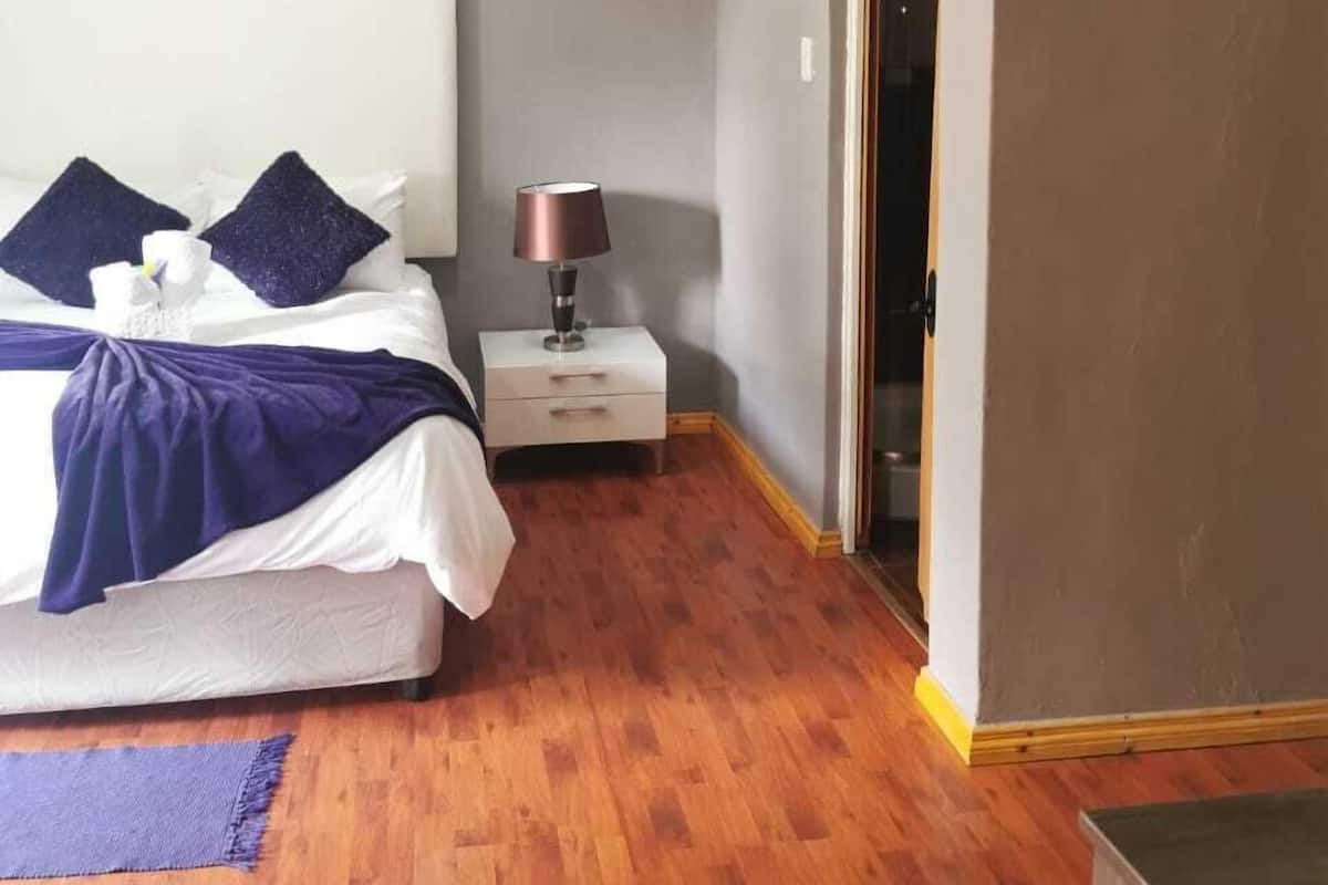 A bedroom with a bed, bedside table, lamp, and a door.