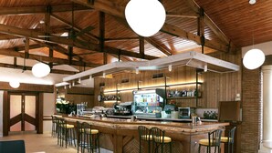 A bar area with a wooden ceiling, bar stools, and a counter with various bottles. - Hotel Juleca (Jaén)