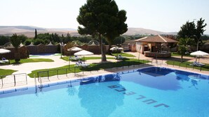 A swimming pool with a clear view of the surrounding area, including a lounge area with sunbeds and a small pavilion. - Hotel Juleca (Jaén)