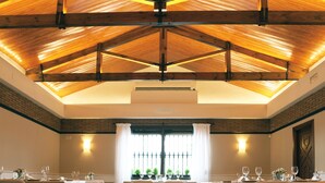 A dining area with tables set for a meal, a high wooden ceiling, and a brick wall. - Hotel Juleca (Jaén)