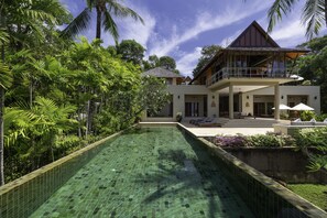 Un resort con piscina, exuberante vegetación y una amplia casa con balcón.