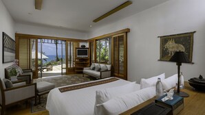 Een hotelkamer met een bed, zithoek, televisie en uitzicht op zee.