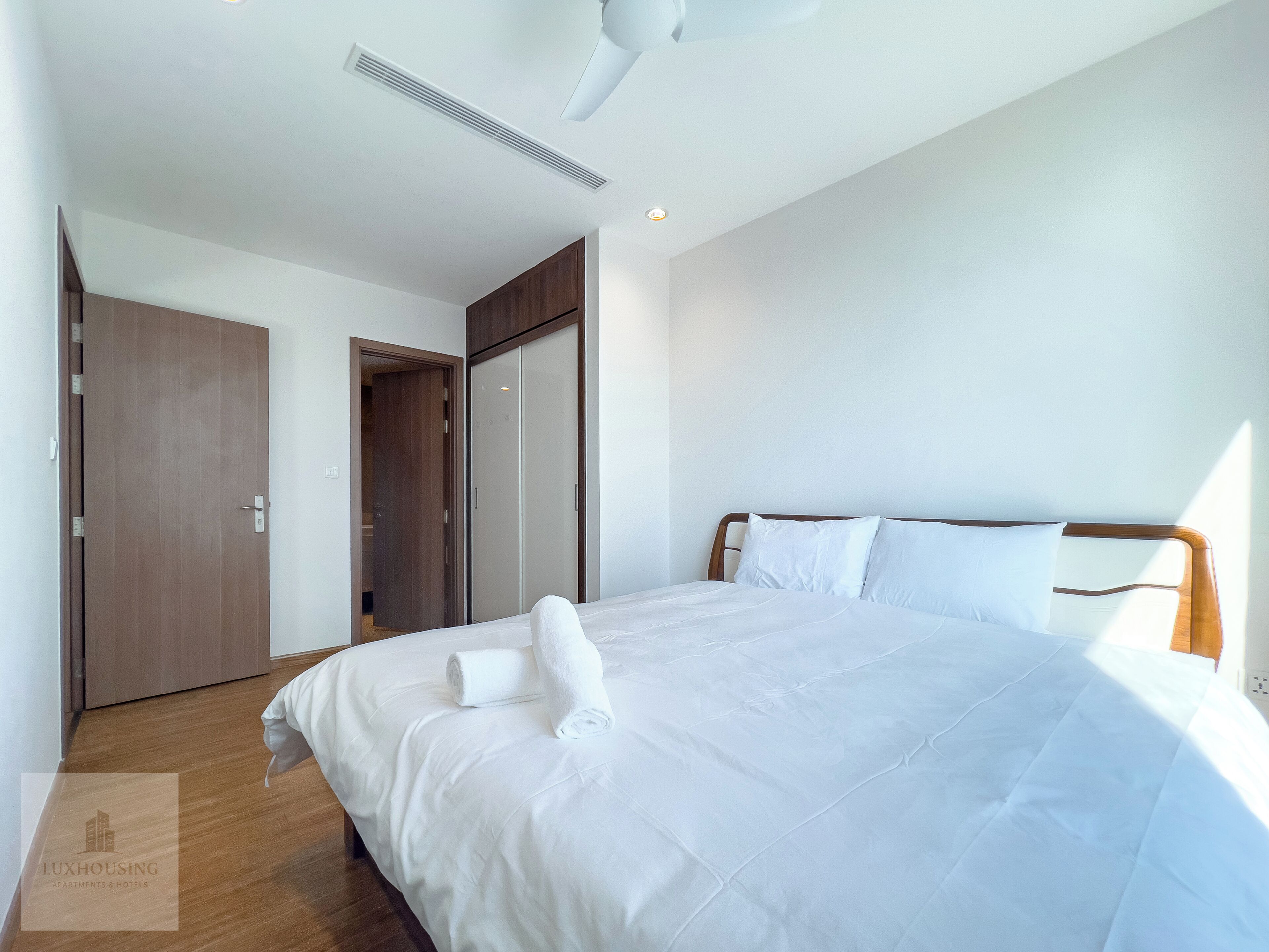 A hotel room with a large bed, a wooden wardrobe, and a ceiling fan.