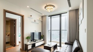 Una sala de estar moderna con un televisor de pantalla plana, un sofá, una mesa de centro y un amplio ventanal con cortinas.