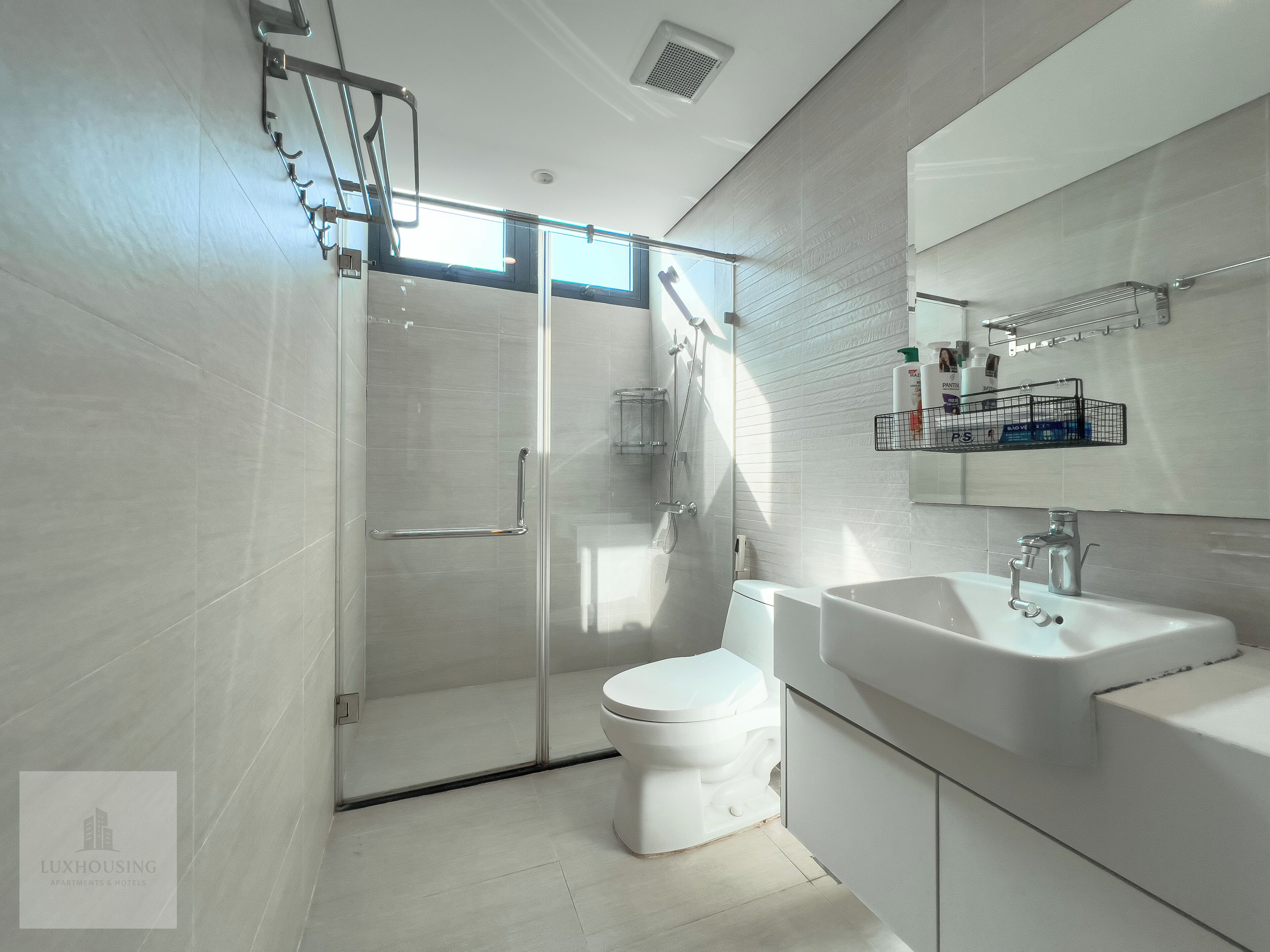 Ein modernes Badezimmer mit Duschkabine aus Glas, Toilette und Waschbecken mit Spiegel darüber.