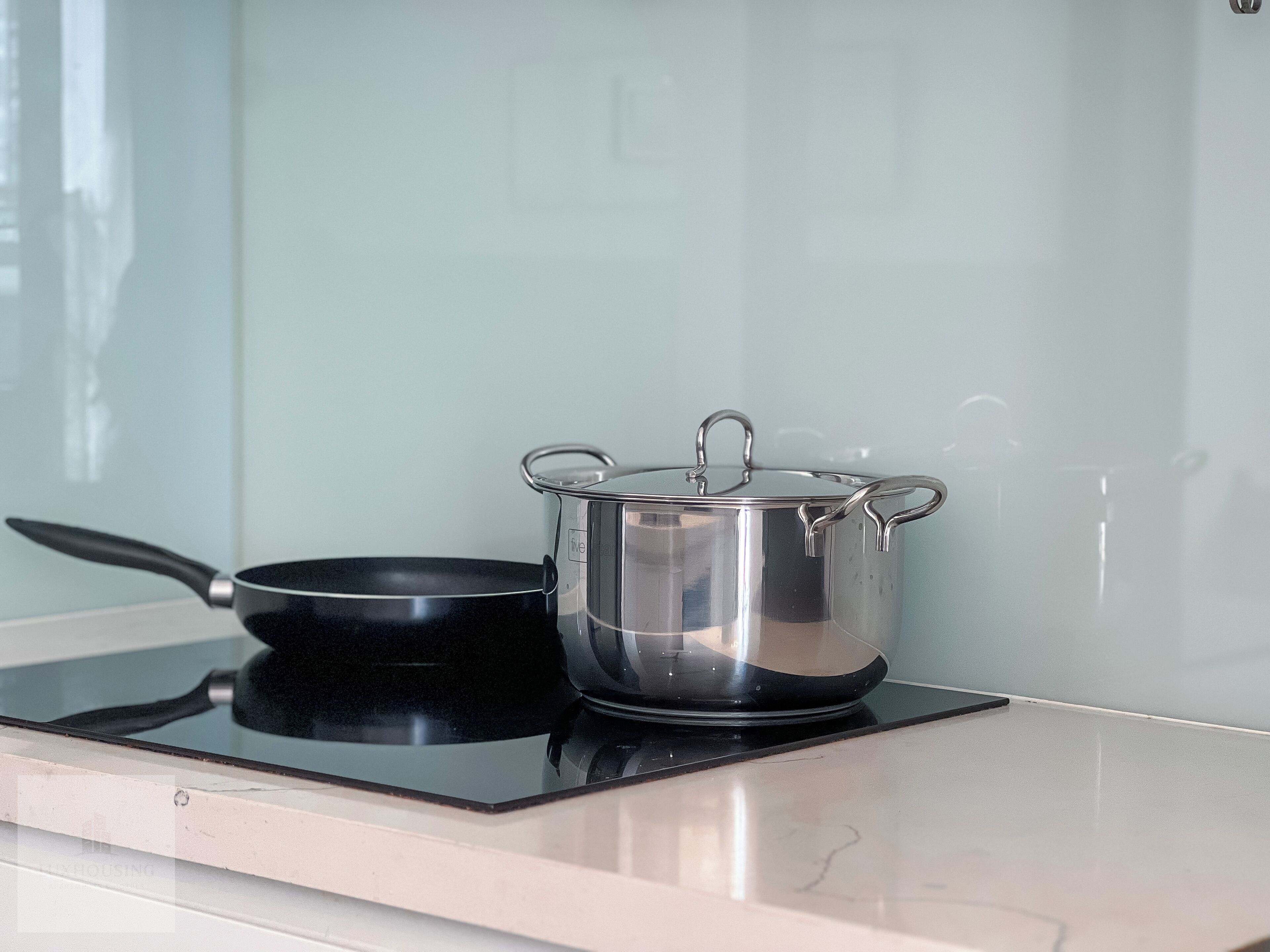 A kitchen with a black induction cooktop and a stainless steel pot with a lid.