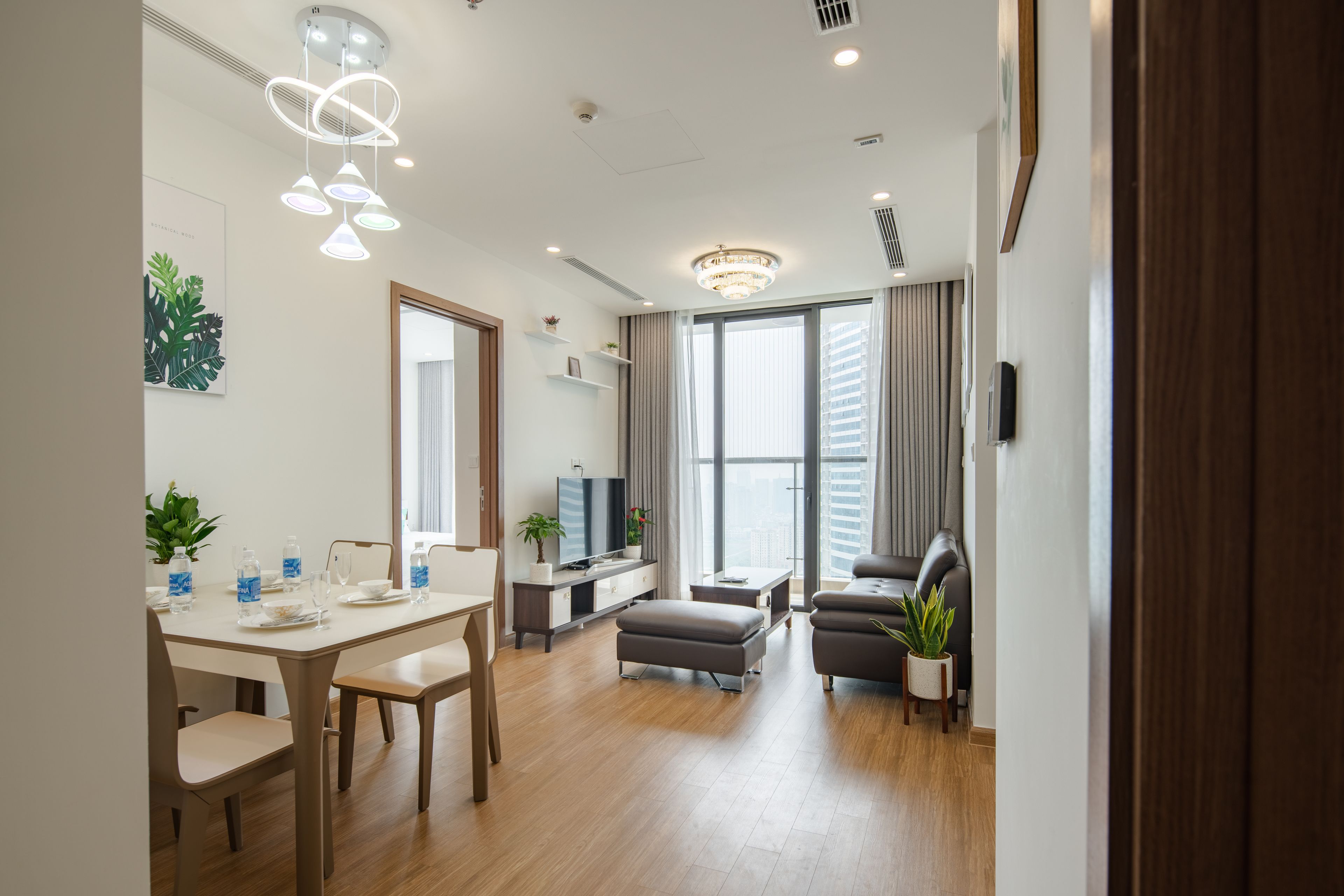 Un salon moderne comprenant un coin repas, un canapé, un téléviseur et une grande fenêtre avec des rideaux.