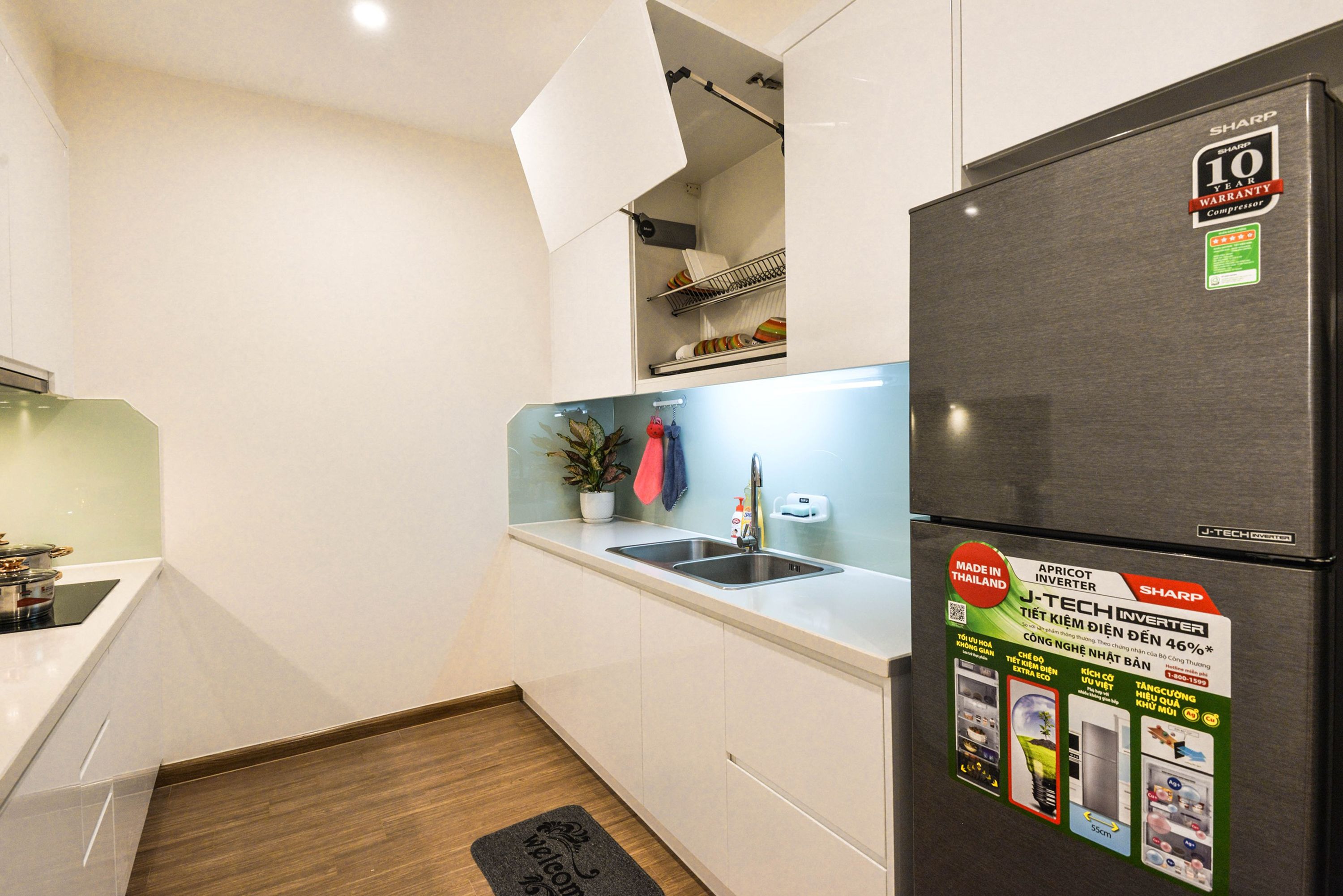 Una cocina compacta con armarios blancos, un refrigerador negro y una pequeña encimera.