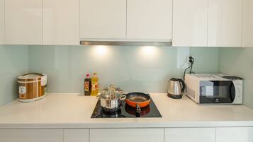 A kitchen with a rice cooker, a pot, a frying pan, a kettle, and a microwave.