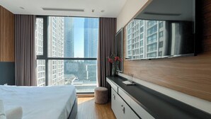 Una habitación de hotel moderna con una cama grande, una tocador con espejo y vistas a edificios altos.