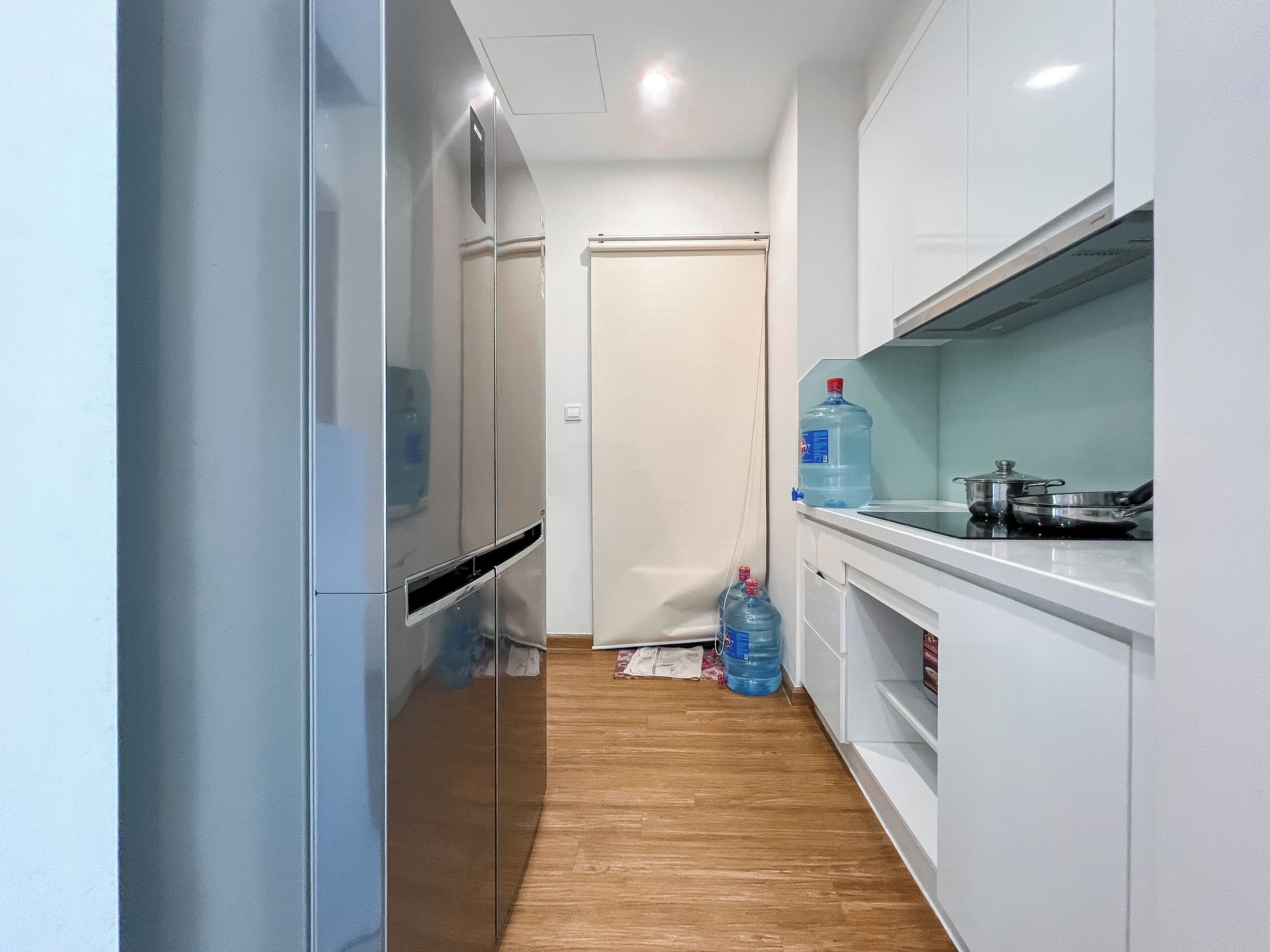 A narrow kitchen with white cabinets, a stove, and a water dispenser.