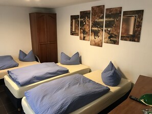 Una habitación de hotel con dos camas individuales, un armario y una pared decorada con cuatro cuadros.