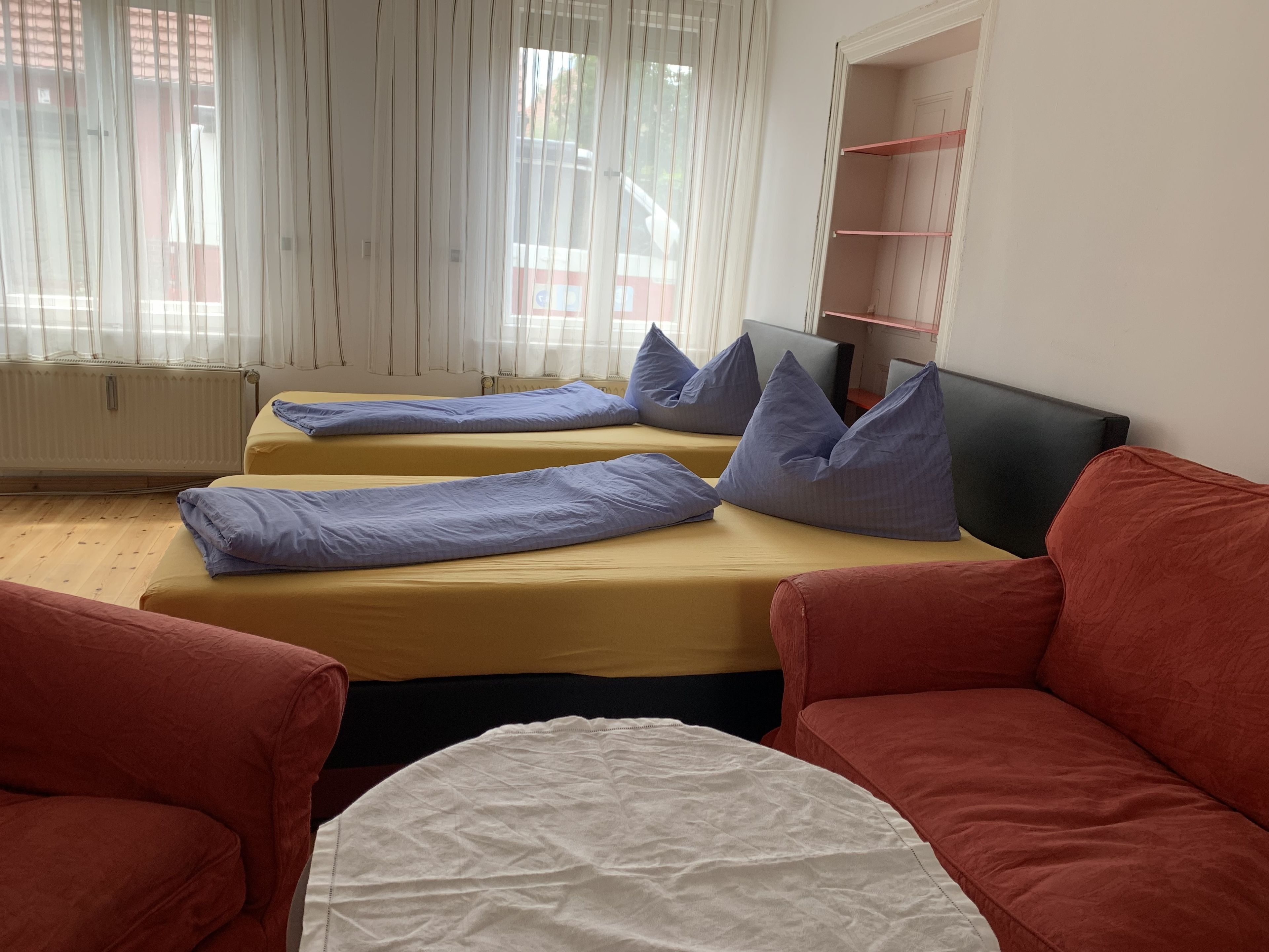 Une chambre avec deux lits, un canapé rouge et un canapé blanc.