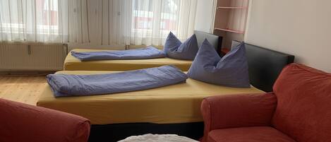 Une chambre avec deux lits, un canapé rouge et un canapé blanc.