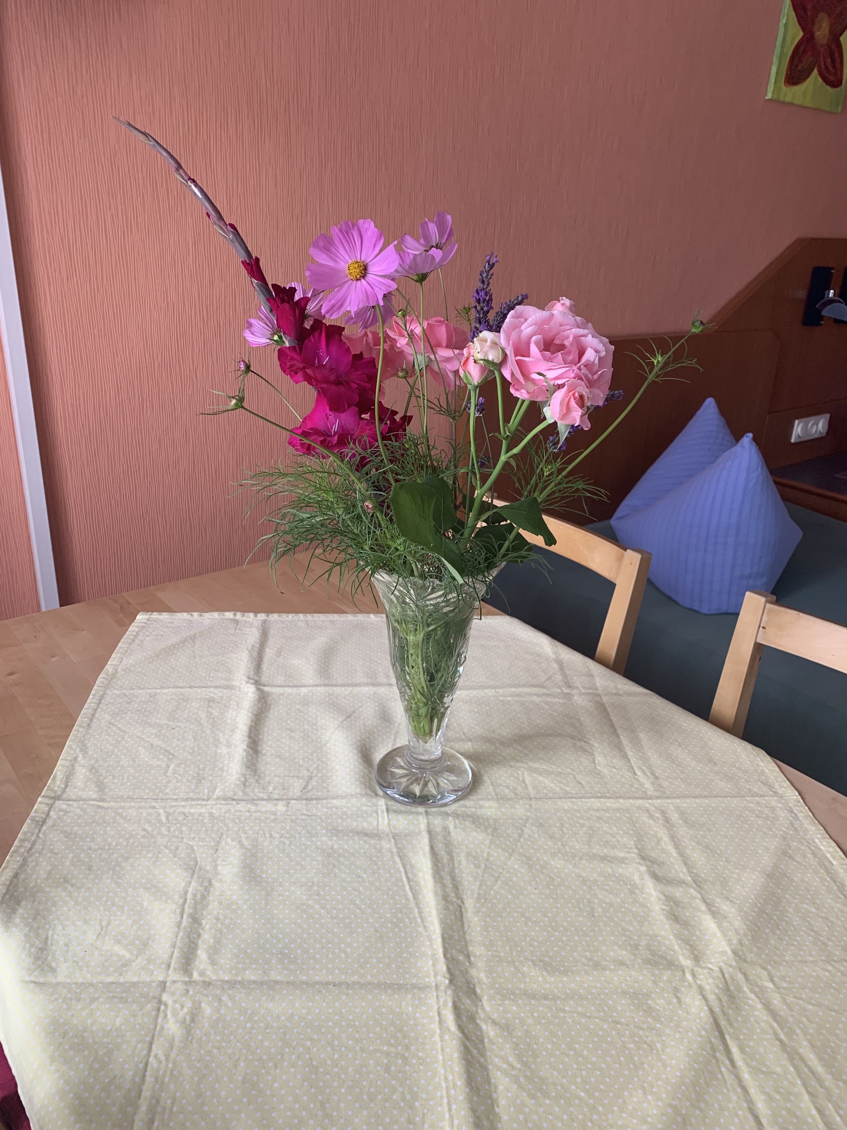 Una mesa con un jarrón de vidrio transparente que contiene diversas flores.