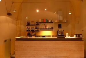 Una zona de bar con estantes llenos de botellas, una máquina de café y una barra.