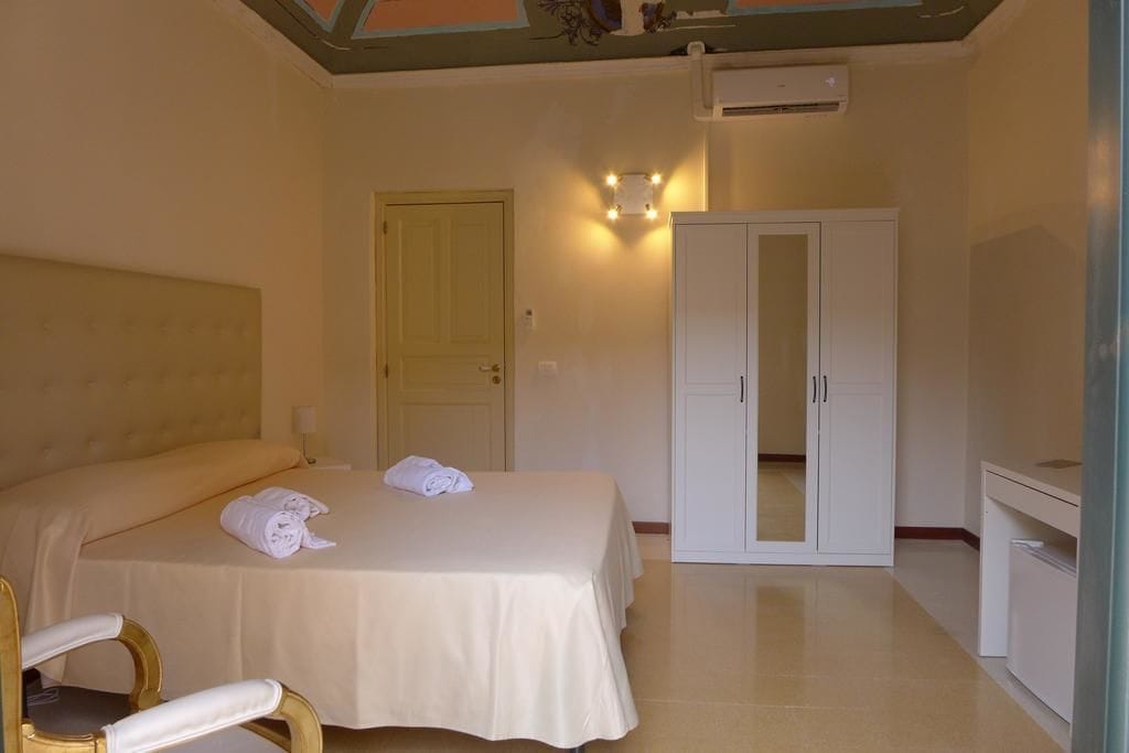 A hotel room with a bed, a wardrobe, a desk, and a chair.