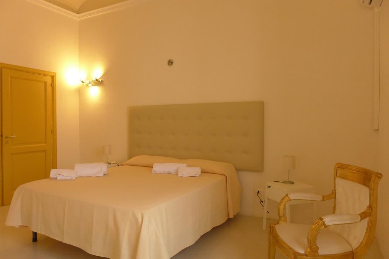 Habitación de hotel con una cama grande, una silla, un escritorio y una lámpara de pared.