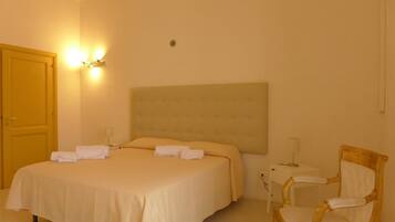 Habitación de hotel con una cama grande, una silla, un escritorio y una lámpara de pared.