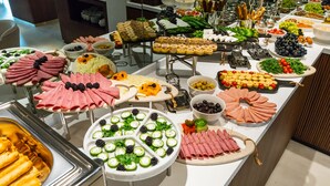 En buffé med ett varierat utbud av mat, inklusive kött, ostar, frukt och grönsaker.